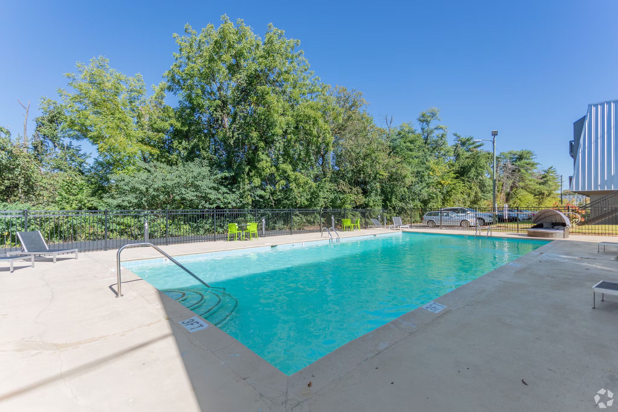 A swimming pool surrounded by trees and a fence.